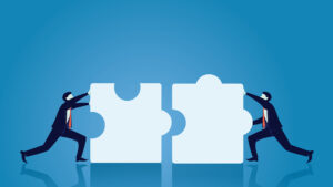 Two businessmen adjoining two large puzzle pieces